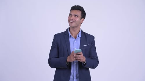 Smiling Young Man Uses Mobile Phone in Studio