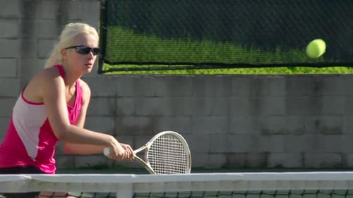 Woman Playing Tennis on Sunny Court Hitting Ball