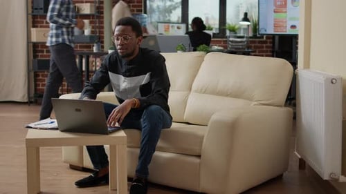 Young Adult Using Laptop on Couch in Office