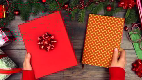 Hands Packing Christmas Gift into Gift Box