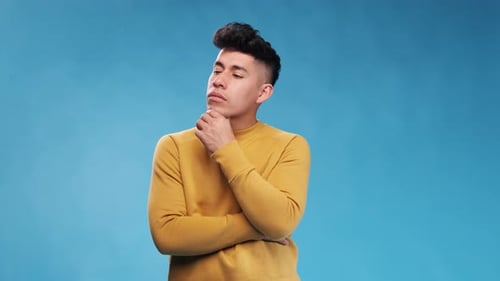 Thoughtful man thinking about something while standing over an blue background.