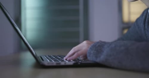 Hands Typing on Laptop Keyboard at Night