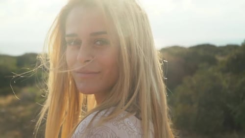 Blond Woman Smiling Near Ocean at Sunset