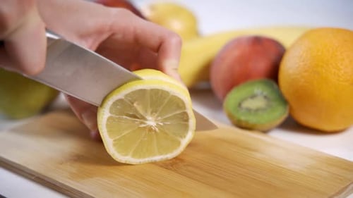 Lemon Slices Being Cut on Cutting Board