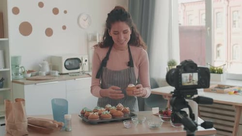 Woman Presenting Cupcakes to Camera in Kitchen
