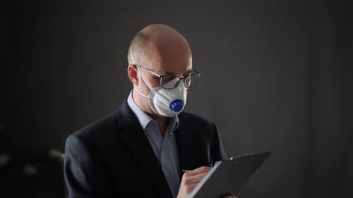 Empresario enfocado en respirador escribiendo en portapapeles