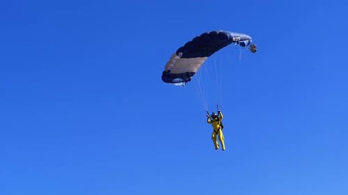 Skydiver Descending with a Parachute in Rural Setting