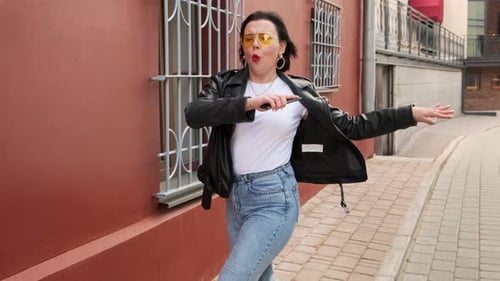 Woman walking the street dancing and listening to the music in mobile phone