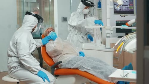 Patient Receives Dental Treatment from Professionals in Protective Suits