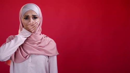 Distressed Woman Covering Mouth on Red Background