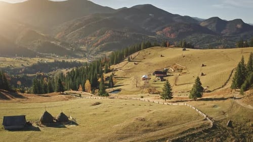 Panorama au ralenti d'une ferme de campagne au coucher du soleil aérien dans un village de montagne