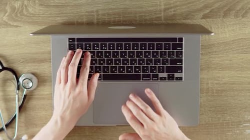 Hands Typing on Laptop with Stethoscope