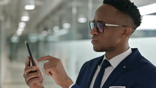 Excited Man in Suit Using Mobile Phone Indoors