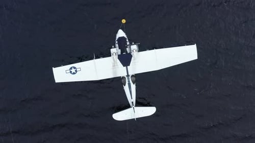 A vintage 1940's Catalina Flying boat anchored in the water. The drone climbs slowly higher while ro