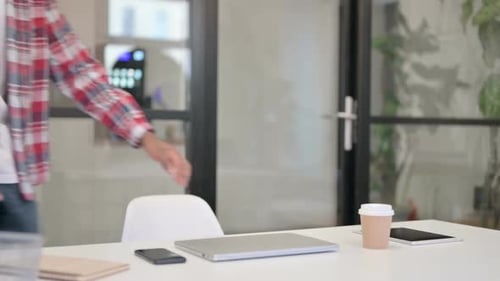 Young Adult Opens Laptop at Modern Office Desk