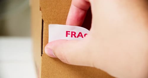Applying Fragile Sticker to Cardboard Shipping Box