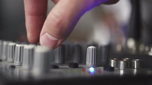Finger Adjusts Audio Mixing Board Knob Close Up