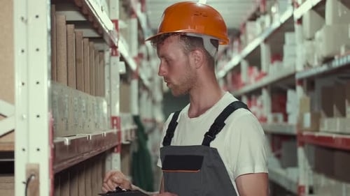 Worker in Helmet Is Checking Materials at the Factory