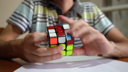 Homem resolvendo o cubo de Rubik - close up, foco seletivo