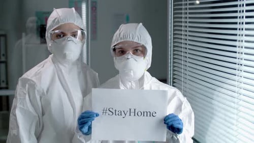 Medical Professionals in Protective Gear Holding StayHome Sign
