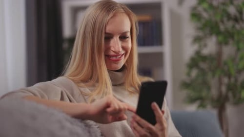 Woman Using Smartphone on Couch in Living Room
