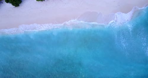 Daytime flying travel shot of a sunshine white sandy paradise beach and aqua blue ocean background