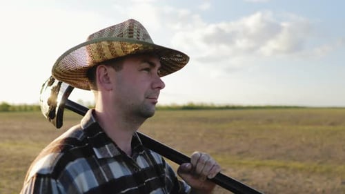 Man Carrying Shovel in Rural Field