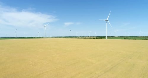 Group of windmills for electric power production in the agricultural fields. Aerial view.