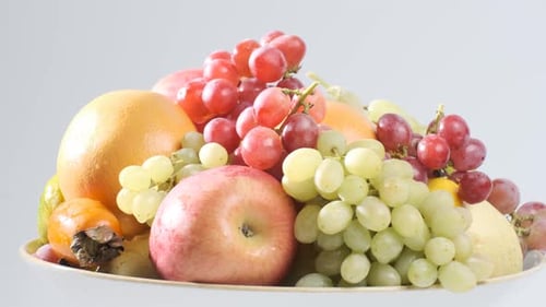 Varios tipos de frutas frescas en un plato blanco que gira frente a la cámara