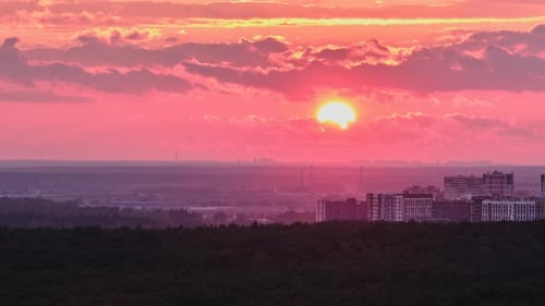 The orange sunset sun sets behind the houses in the evening city, timelapse