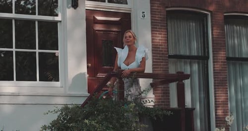 Woman Stands on Urban Home Porch During Daytime