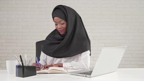African Woman Writing in Notebook