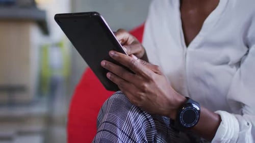 Happy african american woman sitting in cafe using digital tablet and smiling