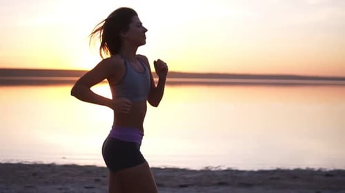 Close Up of a Beautiful Sporty Girl Running Along the Sea or Lake in a Sportswear