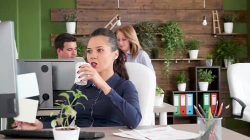 Jeune femme d'affaires concentrée et ambitieuse travaillant sur son ordinateur au bureau