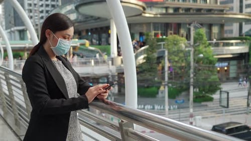 business woman using smartphone and wearing medical mask for protection from coronavirus