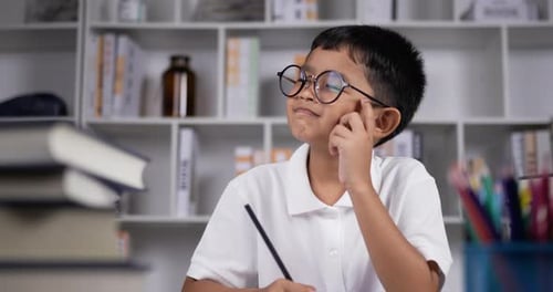 Boy thinking and holding black pencil.