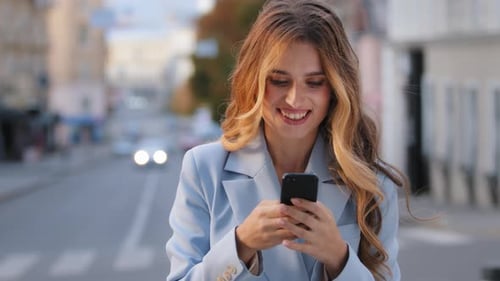 Smiling Woman Using Phone on City Street