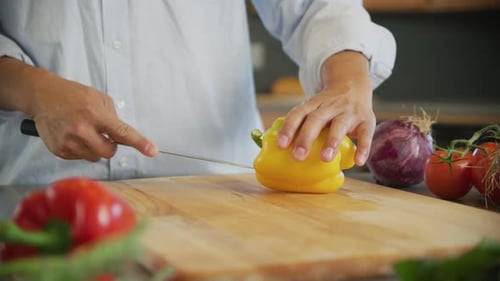 Close up shot of man cutting yellow bell pepper