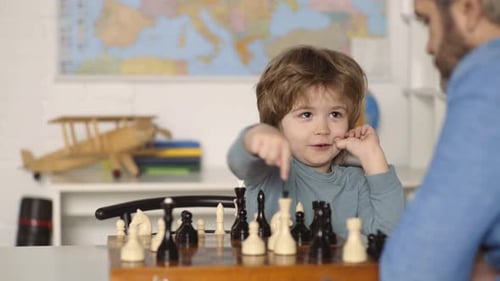 Cute Child Plays Chess with Adult at Home