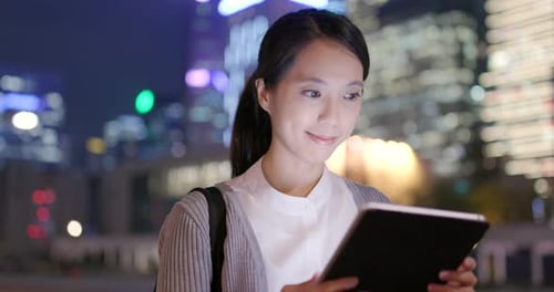 Business Woman Reading on Tablet Computer in City at Night