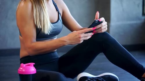 Woman Using Phone After Workout in Gym
