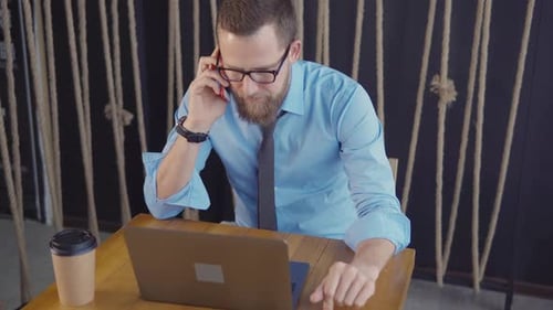 Director of Company Is Talking By Cellular Phone in Office, Looks at Laptop