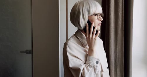 Woman Talks on Phone Near Window