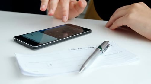 Closeup Footage of Young Businesswoman Calculating Money Before Filling Empty Bank Cheque