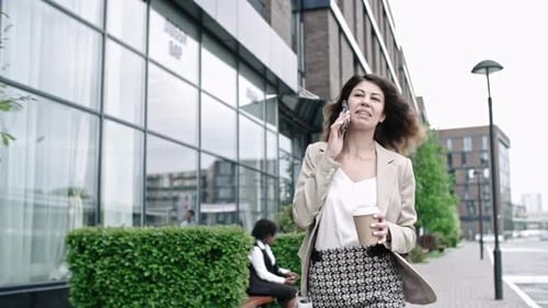 Woman Talking on Phone Walking By Office Building