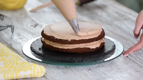 Cream being squeezed onto chocolate cake. Squeezing the cream on the cake.
