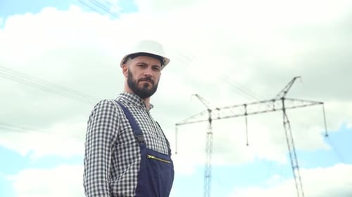 Handsome Engineer Stands Proudly by Power Lines