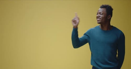 Man Points to the Left on Yellow Background