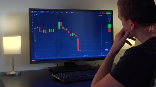 Man Analyzes Stock Market Data on Computer